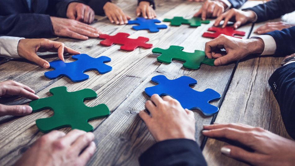 Viele Hände verteilen große Puzzleteile auf dem Tisch