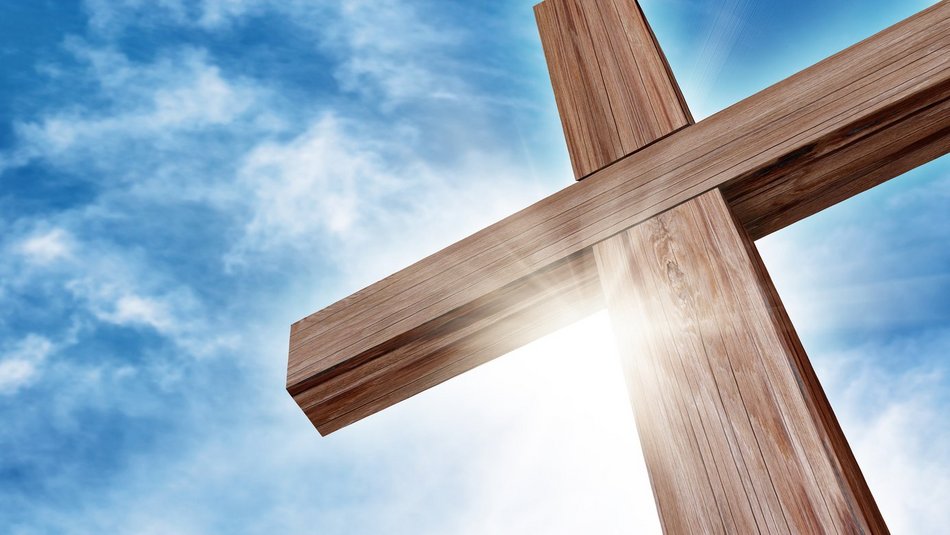Großes Holzkreuz wird von der Sonne angestrahlt mit blauem Himmel mit Wolken im Hintergrund